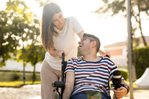 Woman support coordinator pushing man in wheel chair