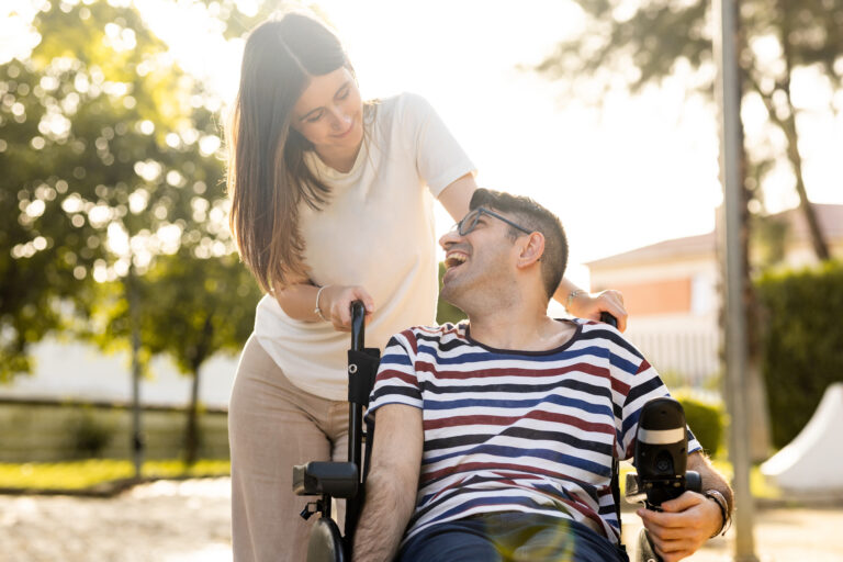 Woman support coordinator pushing man in wheel chair